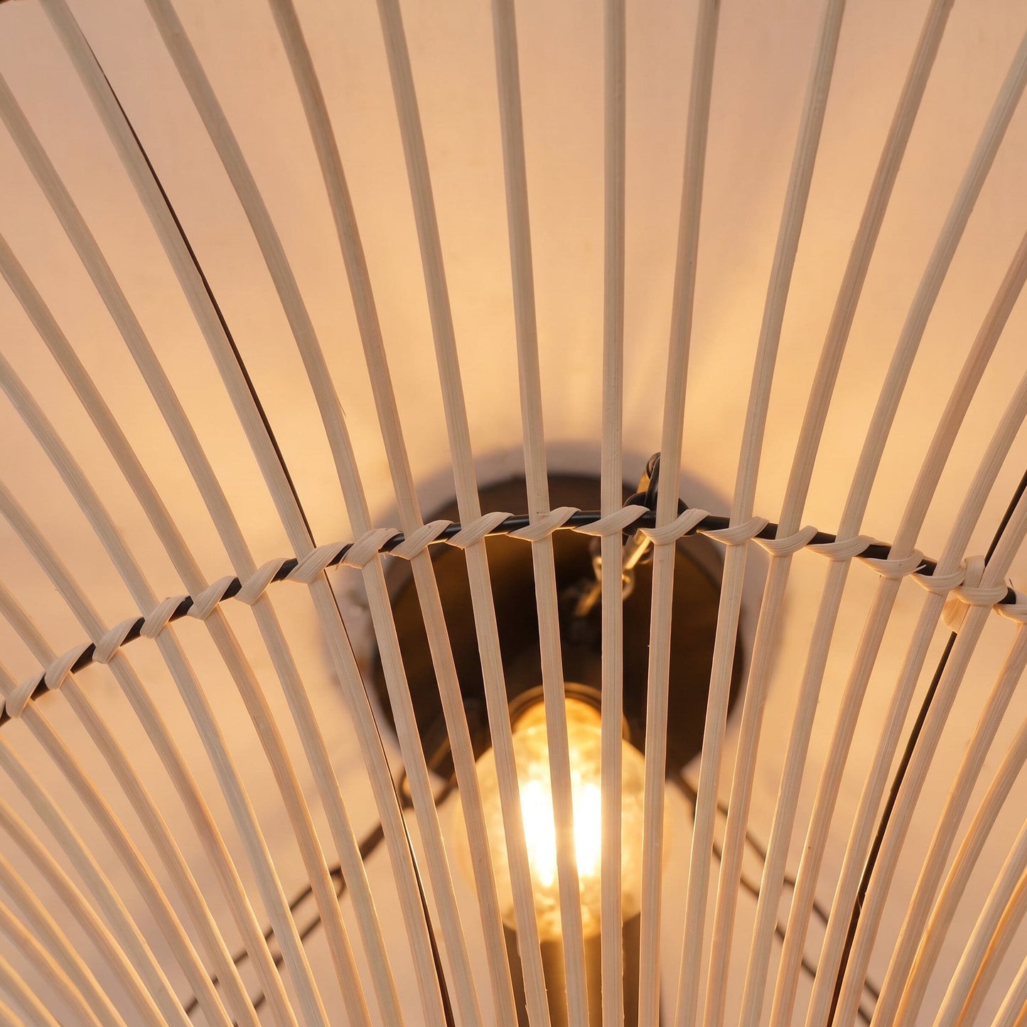 Close-up of warm bulb glowing through the natural rattan saucer shade