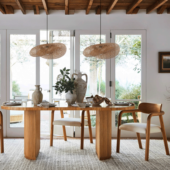 two bamboo pendant lights above a wooden dining table by large windows