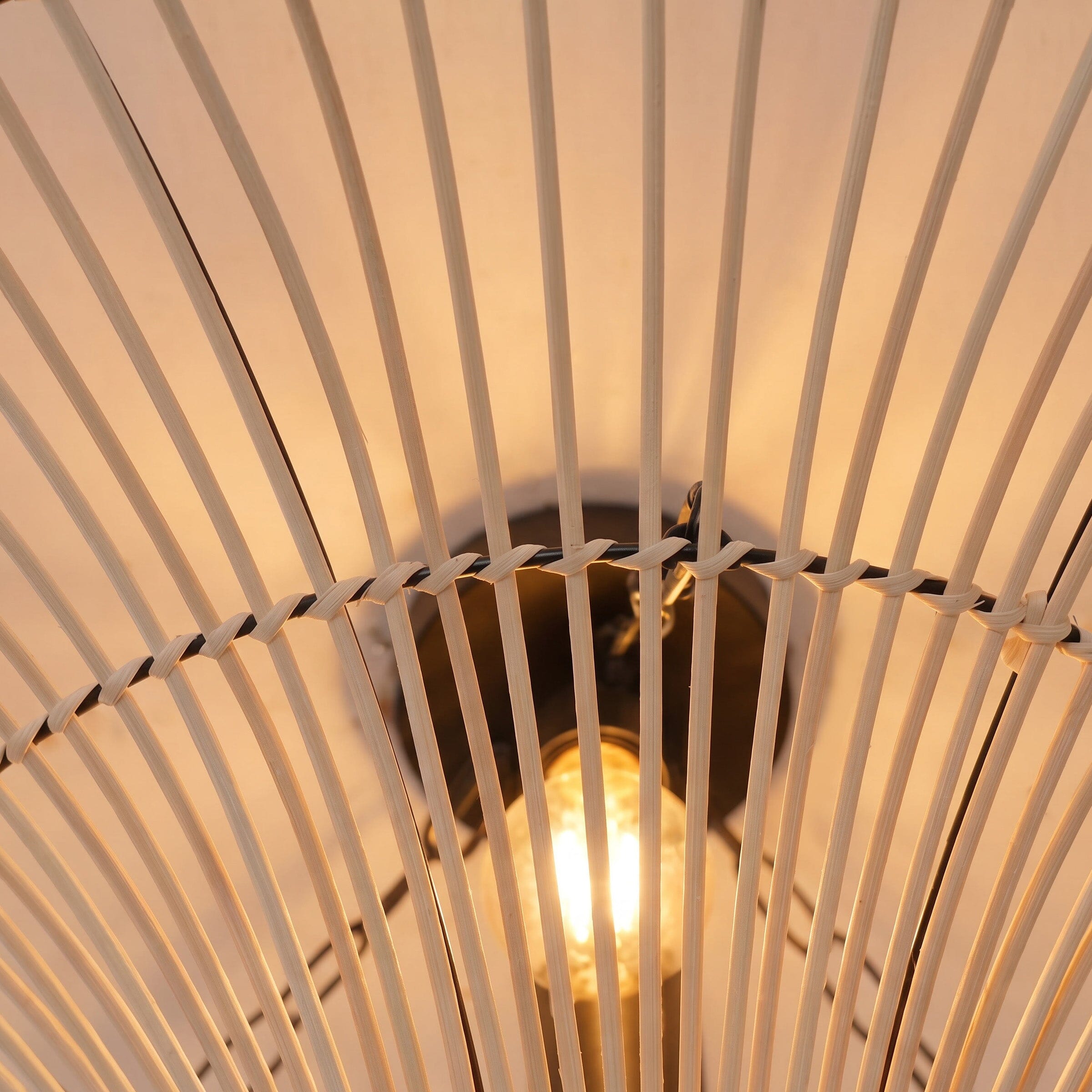 Close-up of warm bulb glowing through the natural rattan saucer shade