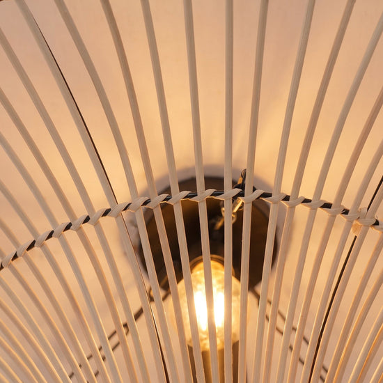 Close-up of warm bulb glowing through the natural rattan saucer shade