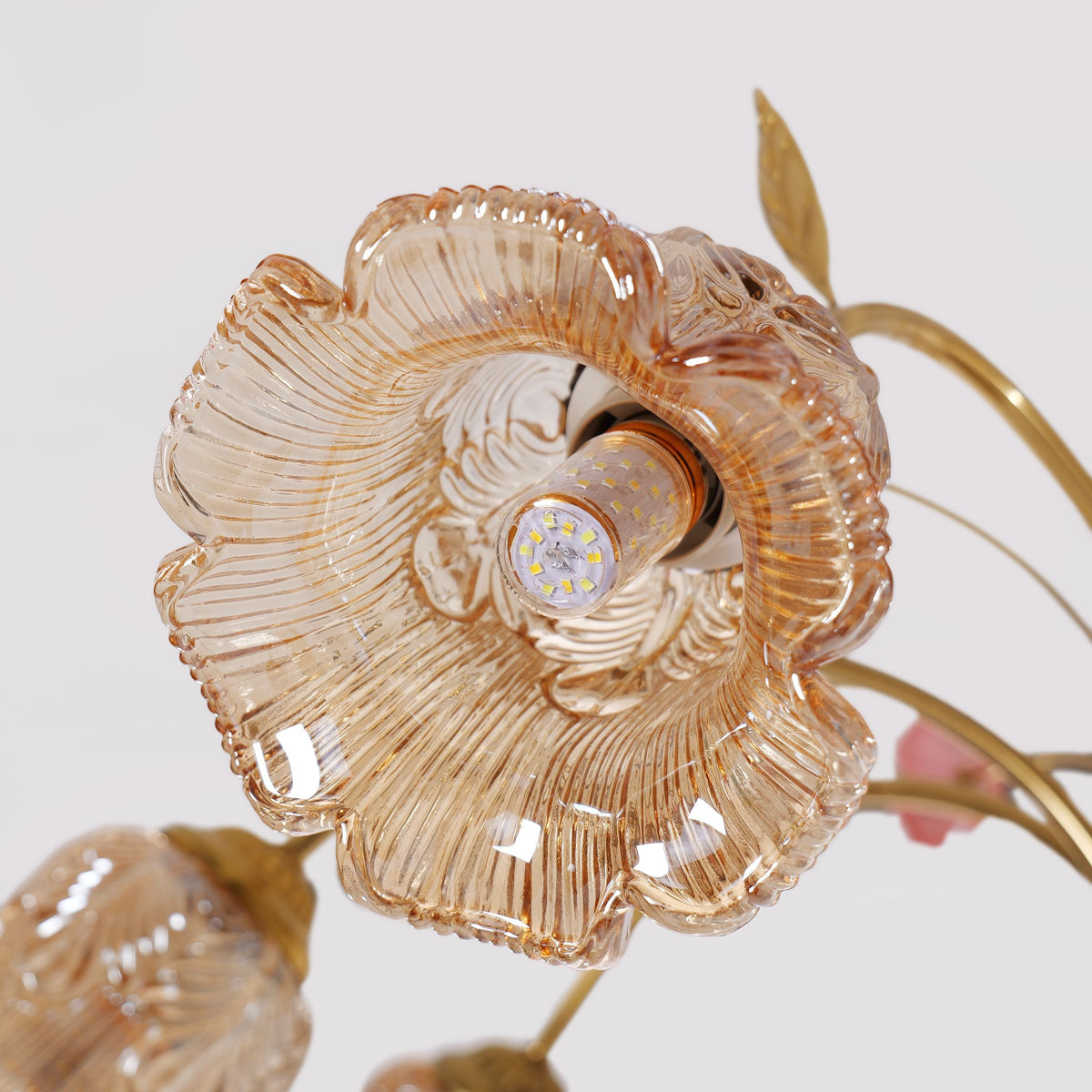 gold 8-light chandelier with pink floral glass shades glowing above a dining table