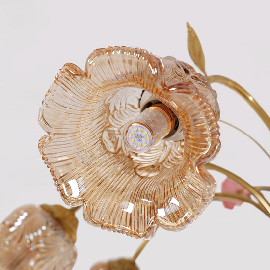 gold 8-light chandelier with pink floral glass shades glowing above a dining table