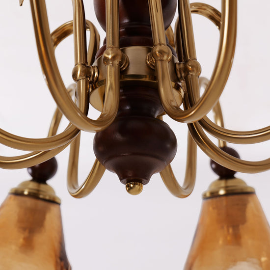 8-light walnut chandelier with amber cut glass shades glowing above a dining table