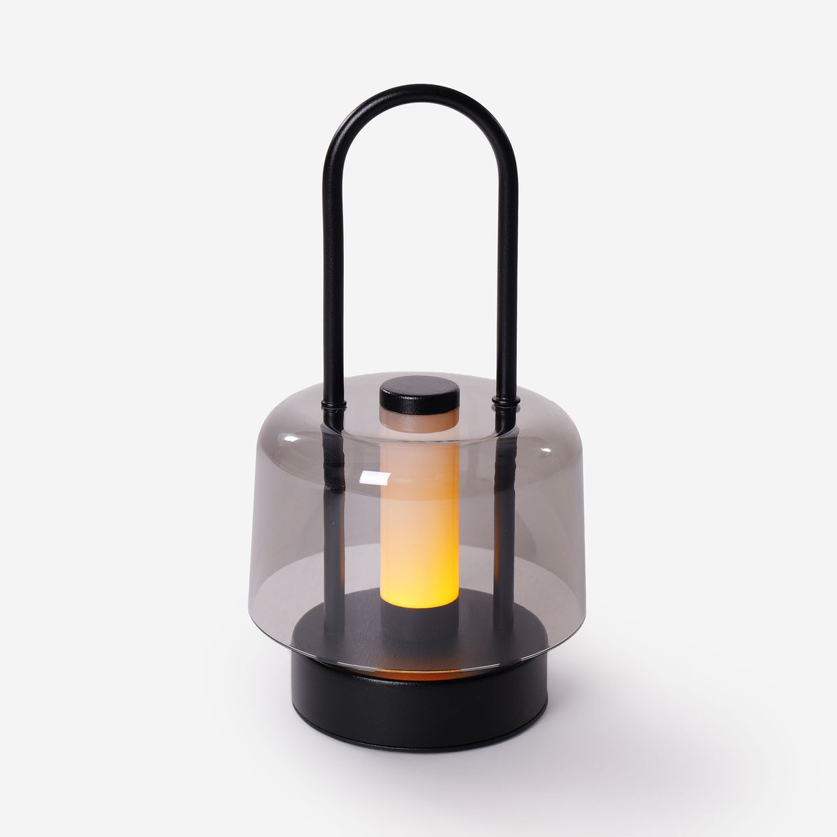 portable lantern-style ambient table lamp glowing on a bedside table