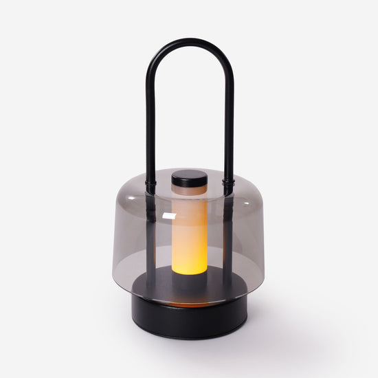 portable lantern-style ambient table lamp glowing on a bedside table