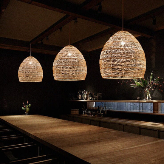 Three rattan pendant lights above a long restaurant bar counter