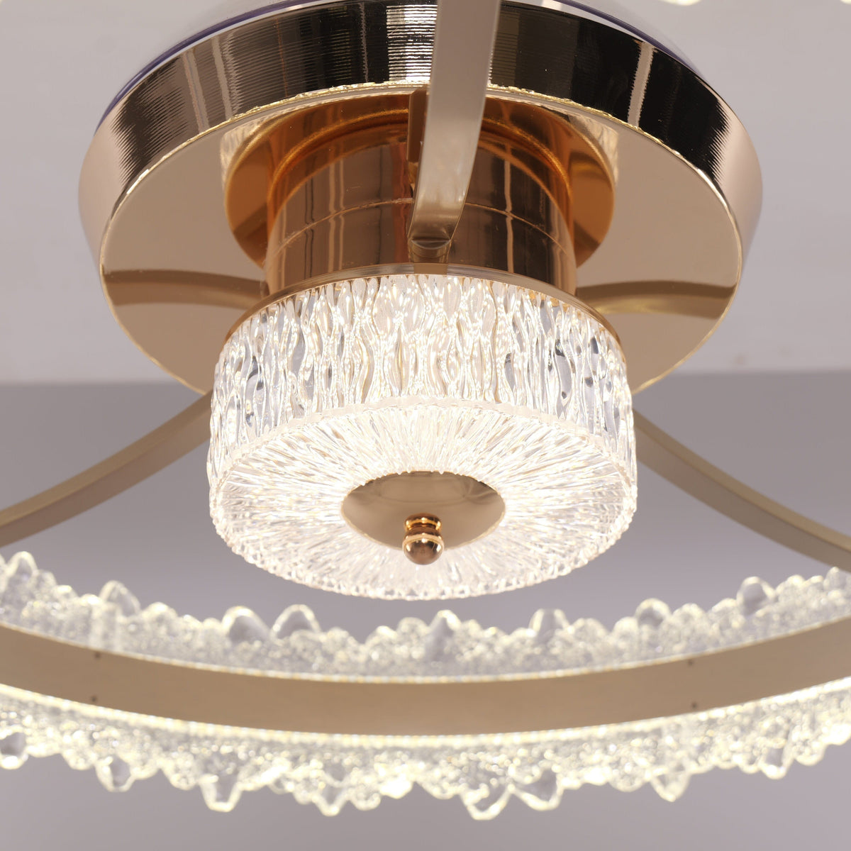Underside close-up of gold ceiling fan light with clear blades and crystal diffuser